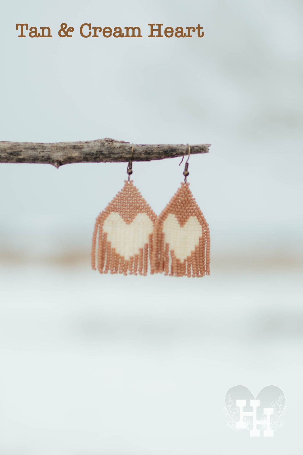 Seed bead earrings layed out on the ground. Set in cream with a tan heart, cream with a red heart, cream with a pink heart, and tan with a cream heaert. Earings are 1 1/4 inches wide and 2 1/2 inches long.