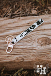 Cow hide wristle key chain with gold key ring and clip. Leather is black and white spotted.
