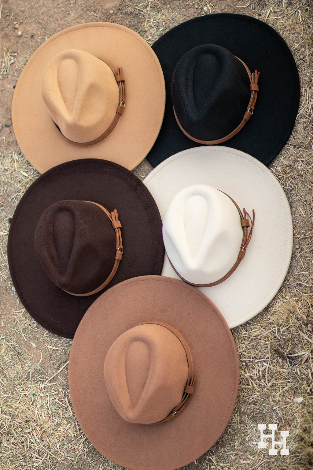 5 different colored wide brim hats with brown leather strap around each one. Top left hat is light kahki, top right hat is black, middle left hat is dark brown, middle right hat is cream, and bottom is dark kahki. 