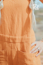 Close up of orange linen overalls show it's waffle texture.