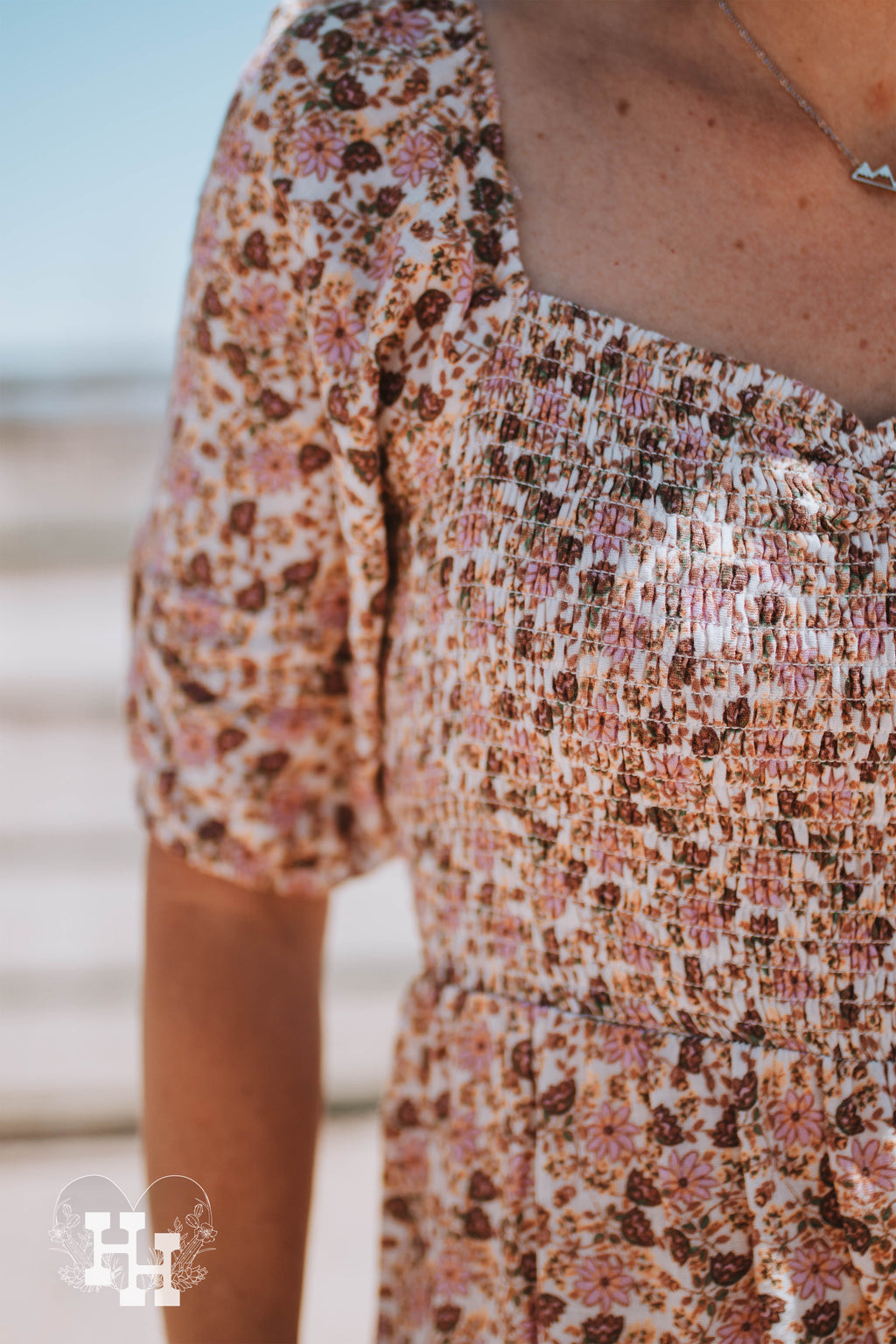Close up of smocked bodice, sweetheart neckline and puff sleeves on a pink, brown, and floral maxi dress.